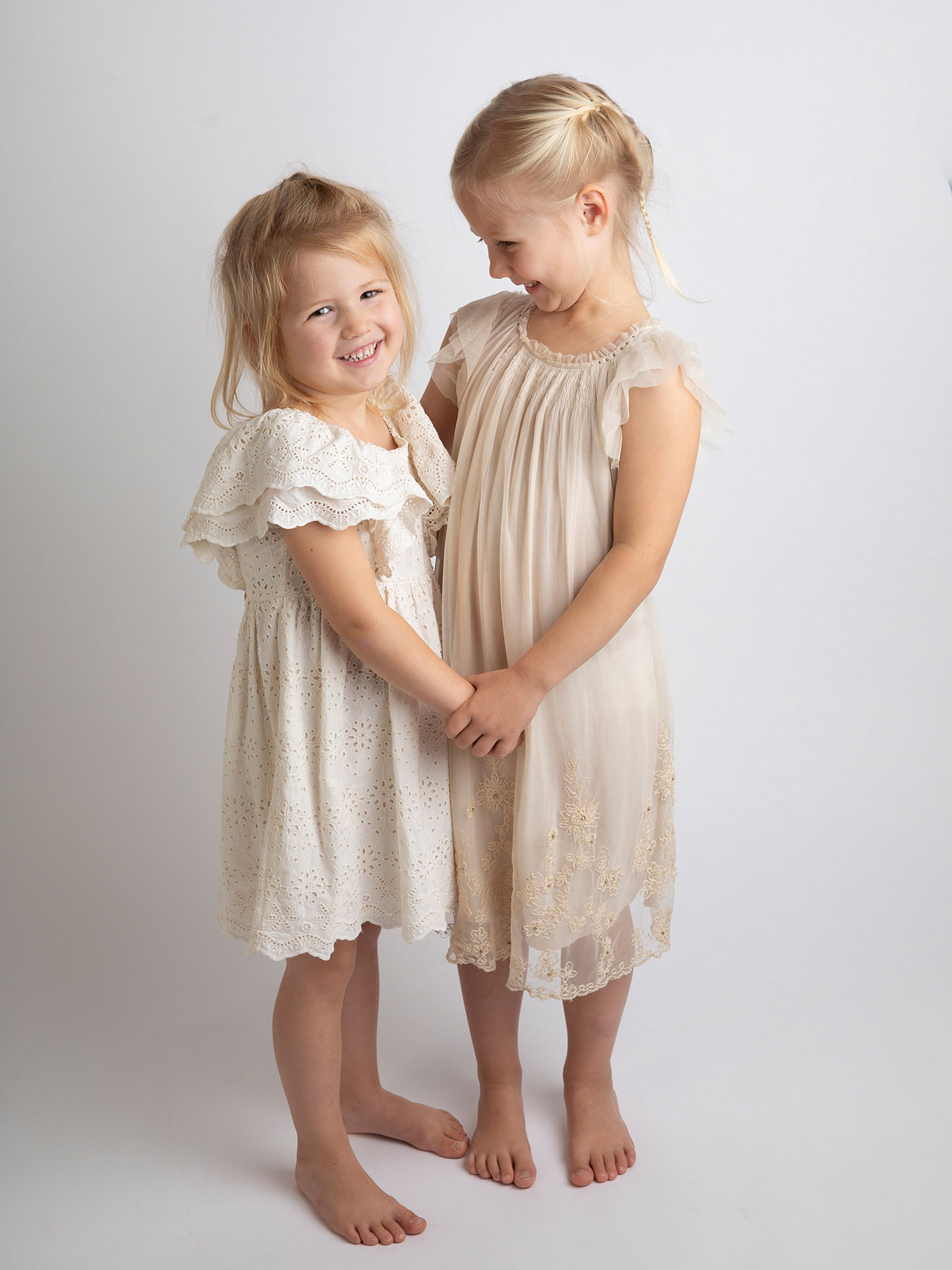 Två systrar fnittrar och håller hand när de blir fotograferade i studion i Malmö.