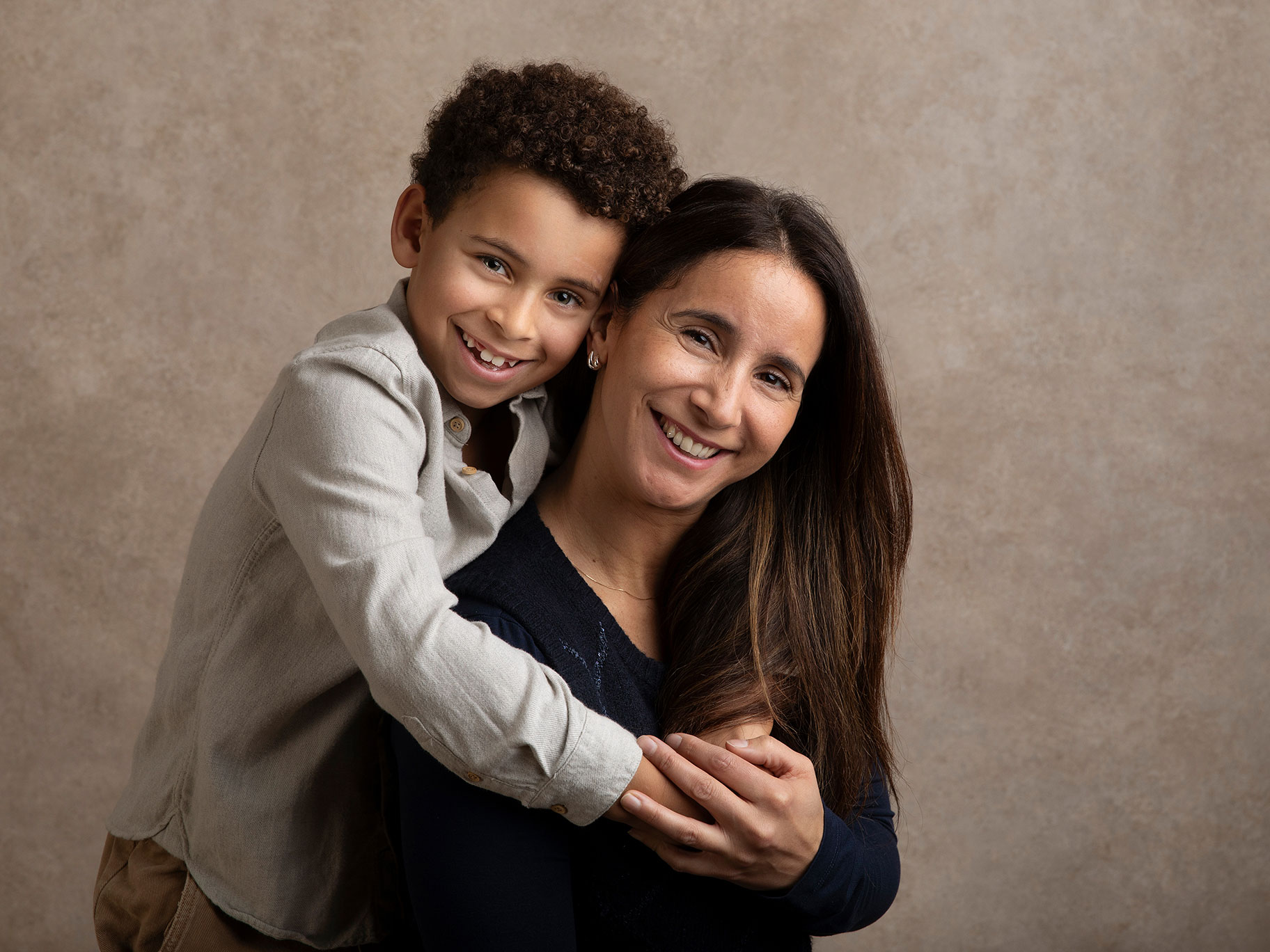 Glad bild tagen i en fotostudio på en mamma med sin son som håller om henne.