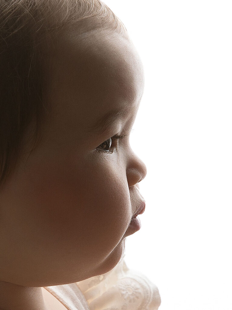 Närbild på babyansikte i profil med vit bakgrund.