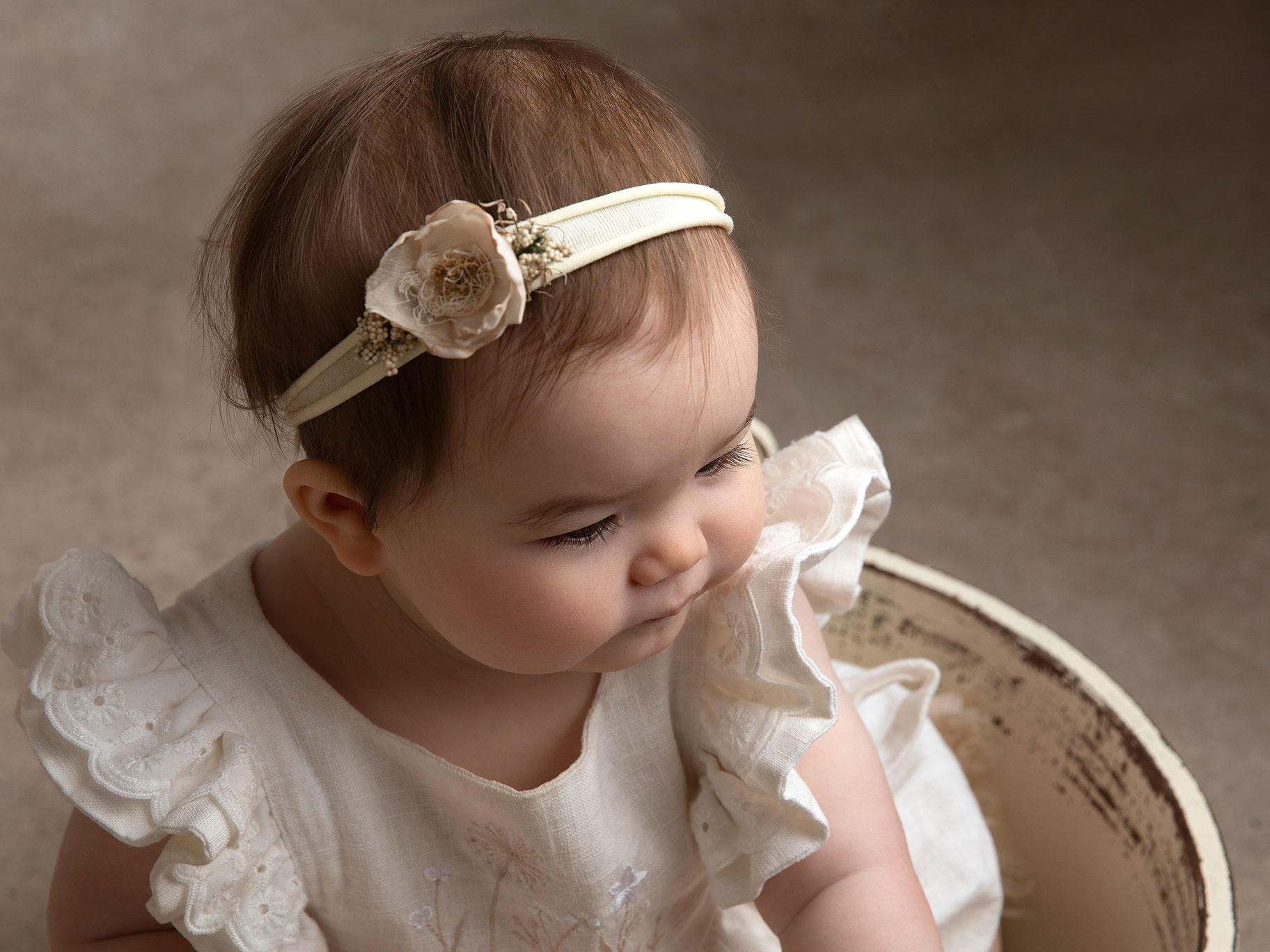 Babyflicka tittar ner i baljan hon sitter i.