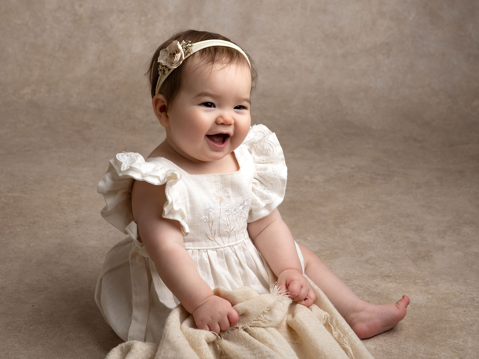 Baby sitter och ler med filt i handen.