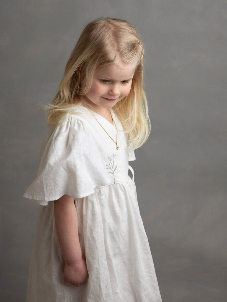 En fin bild på en liten flicka med blont hår som tittar ner.