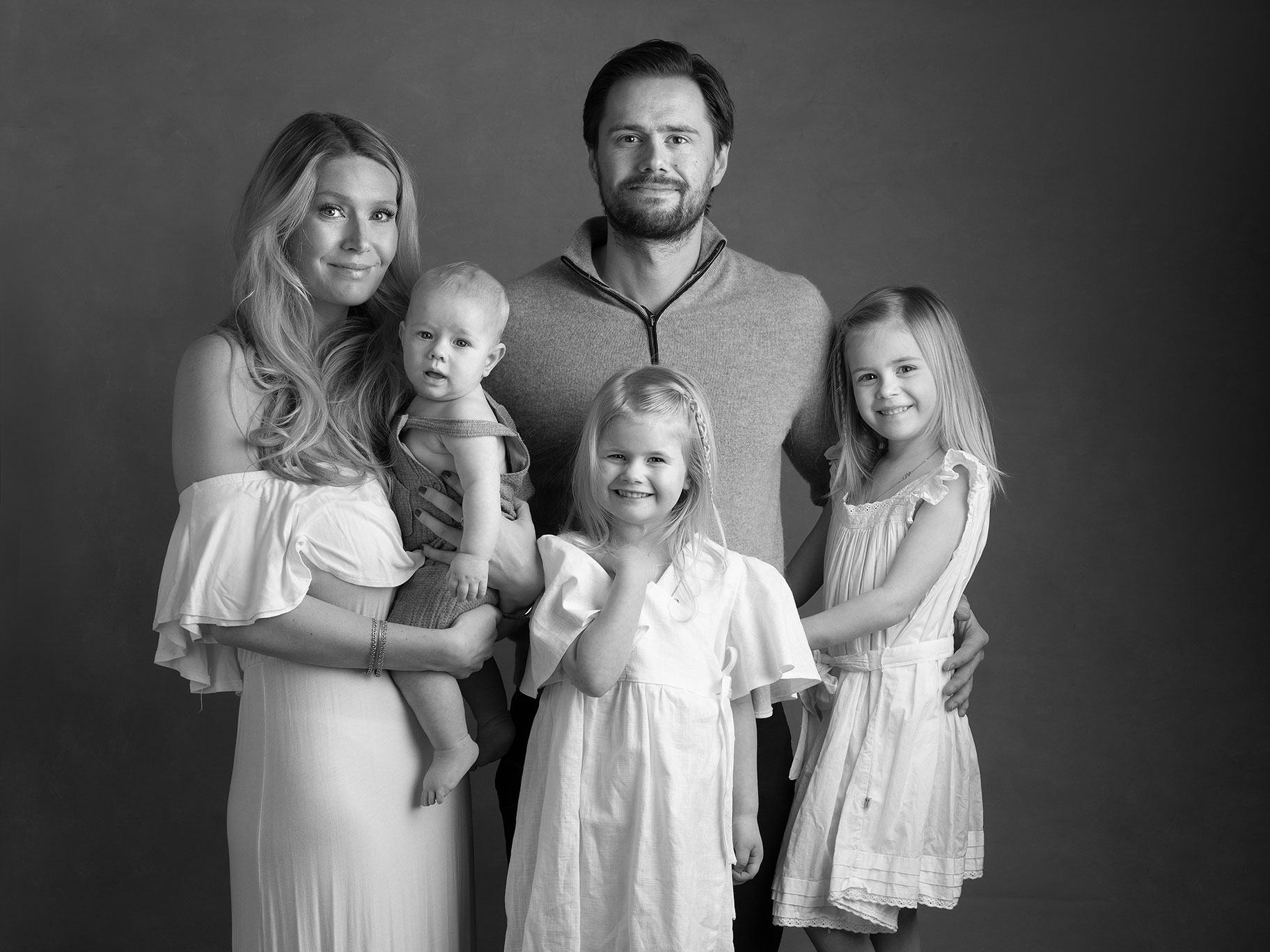 Svartvitt fotografi på en familj med tre barn där alla tittar mot kameran.