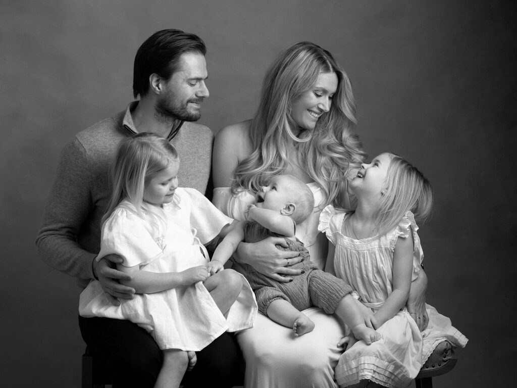Svartvit familjebilder där alla tittar på varandra och skrattar hos fotografen Anna Arvidsson i Malmö.