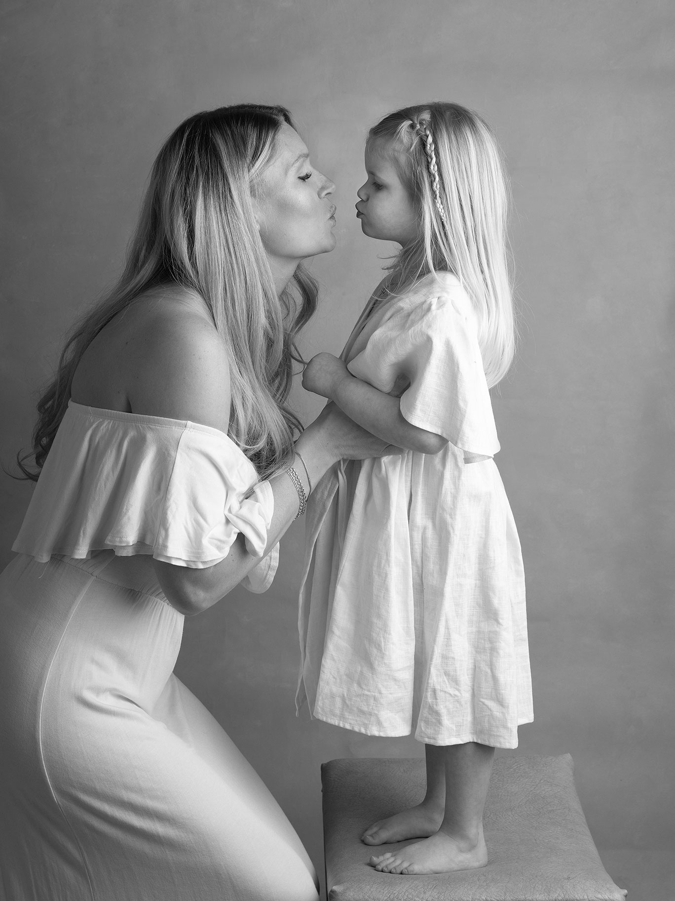 Mamma böjer sig fram och pussar sin lilla flicka.