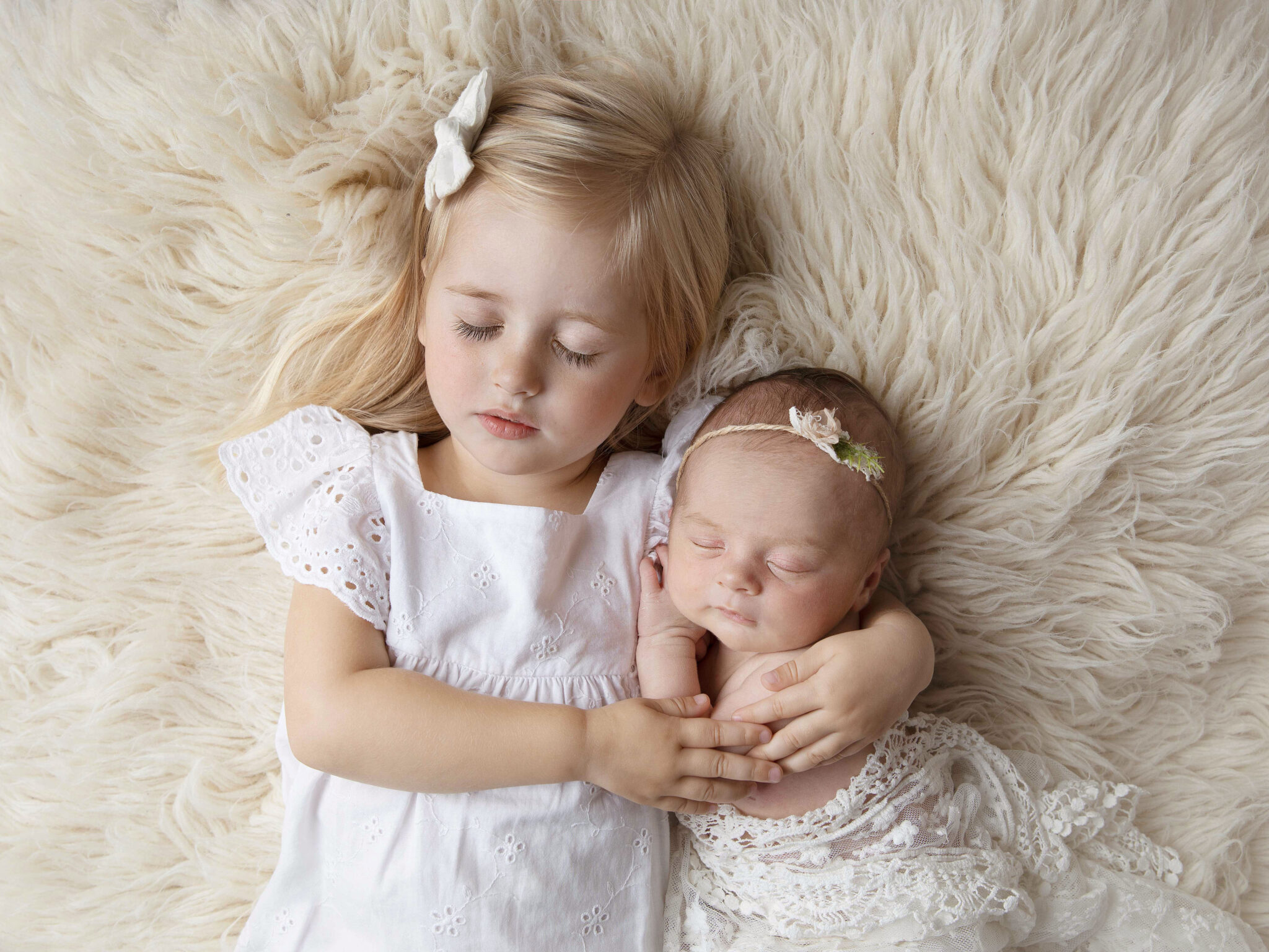 Storasyster med liten nyfödd lillasyster i famnen, bild tagen av fotograf Anna Arvidsson i Malmö.