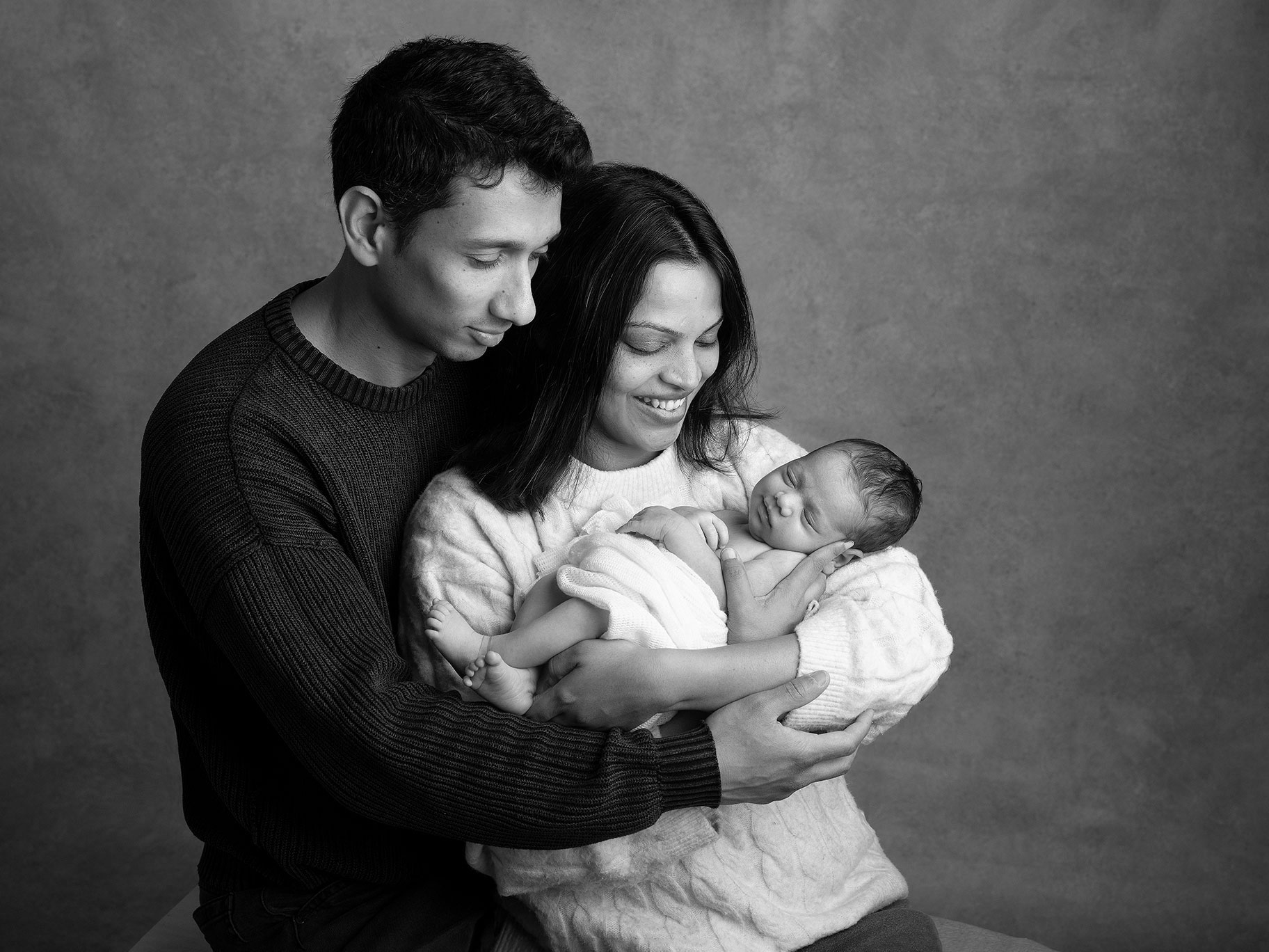 Mamma och pappa som håller sitt nyfödda barn i famnen under en fotografering av Anna Arvidsson.