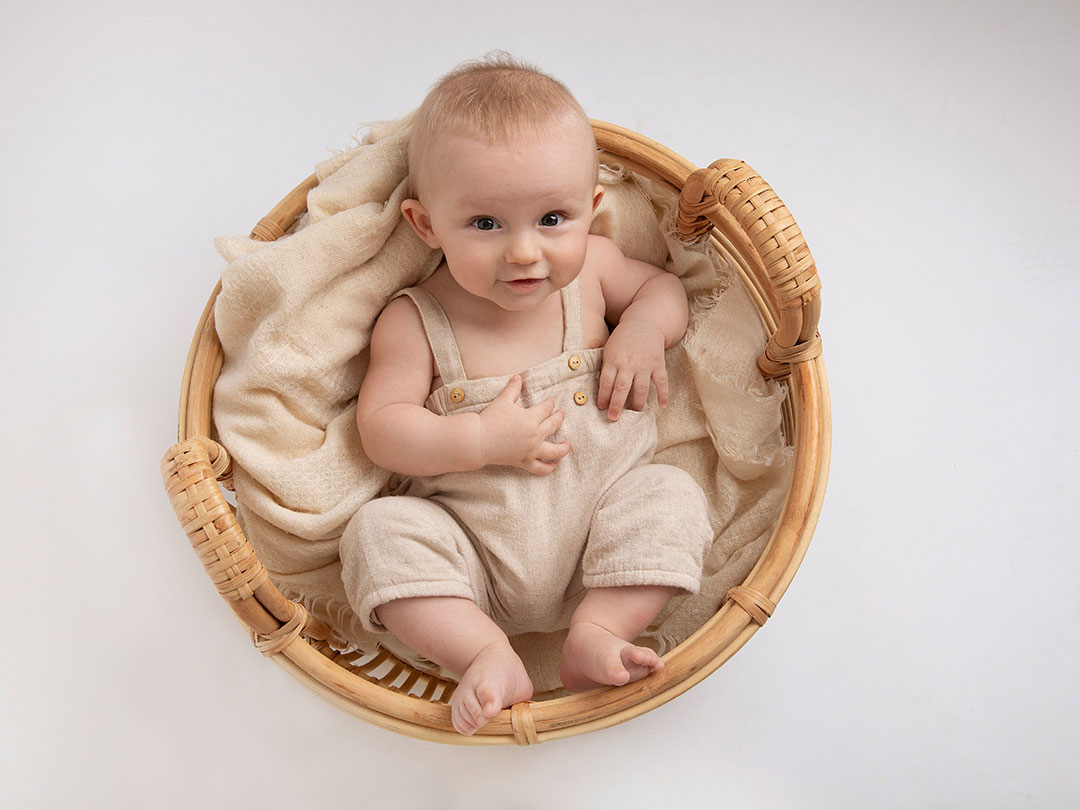 Liten baby pojke som ligger i en korg under en fotografering i Malmö.